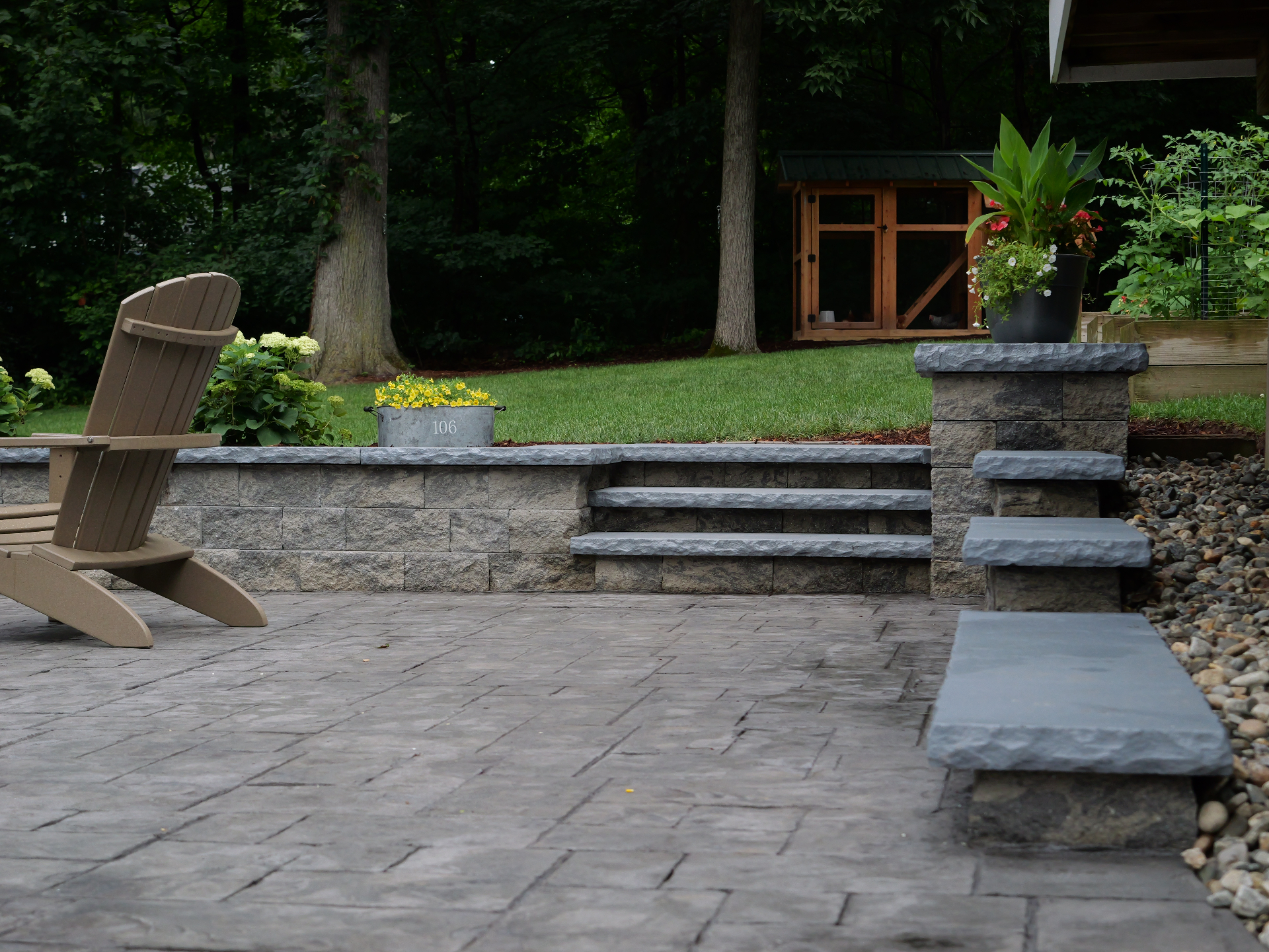 Block retaining wall with bluestone-capped steps beside a stamped patio